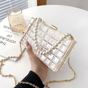 Sac bandoulière en acrylique matelassé avec poignée perle et chaîne dorée, style lifestyle