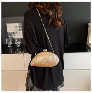 Close-up of amber texture acrylic clutch bag with gold chain and elegant ball clasp