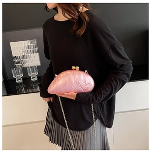 Chic pink pearlescent acrylic clutch bag worn as a shoulder bag with gold chain strap