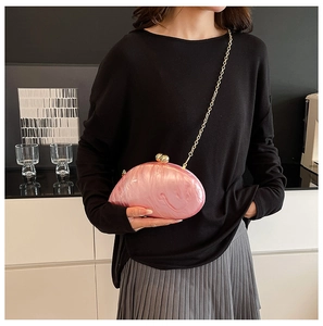 Detail of pink acrylic shell clutch bag featuring marble texture and gold chain strap