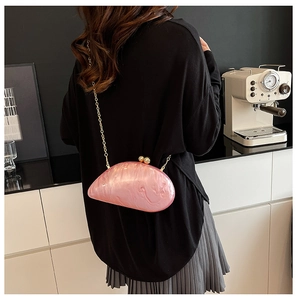 Pink marble acrylic slug-shaped clutch bag with gold chain shown on a model