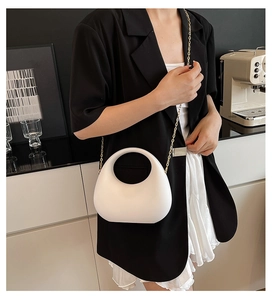 Schicke weiße Tasche mit rundem Hohlgriff und eleganten goldfarbenen Kettendetails