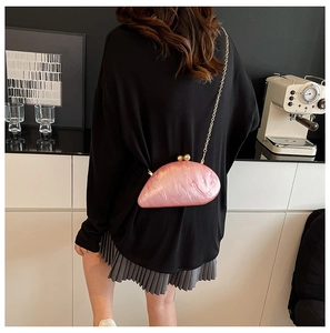 Detail of pink pearlescent acrylic clutch with gold chain strap on a model's back
