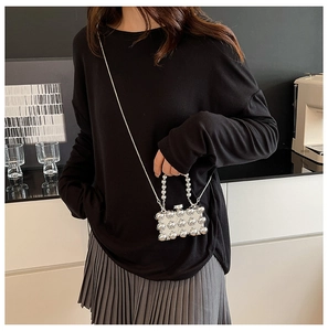 Detailopname van mini zilveren kralenbox tas met metalen textuur en kettingriem