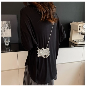 Zilveren mini-pareltas met metalen ketting als crossbody-tas gedragen door model