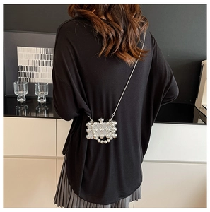 Detail van mini parel crossbody tas met zilveren metalen frame en fijne ketting