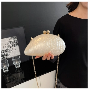 Detail view of pearlized acrylic clutch showing the elegant gold spherical clasp and chain