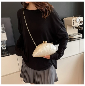 Detail of white acrylic clutch with gold ball clasp and chain, styled with evening wear