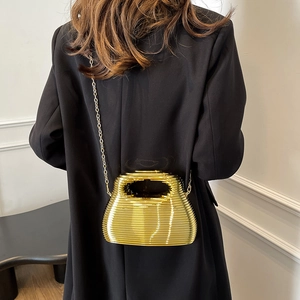 Elegant gold wavy evening clutch with chain strap shown on a professional black suit outfit