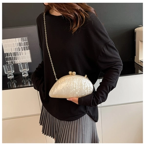 Detail of pearlescent acrylic clutch with marble texture and golden metal chain strap