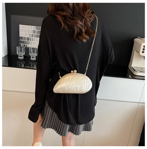 Detailed view of the shell-shaped evening bag featuring iridescent pearl texture and chain