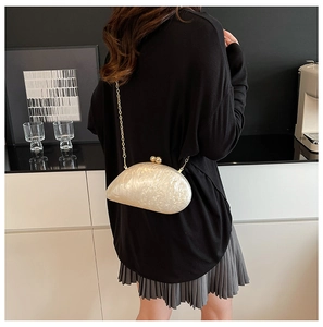 Detail of shell-shaped acrylic clutch bag with marble texture and gold chain strap