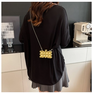Detail van een mini gouden acryl crossbody tas met 3D bolletjes textuur en een ketting