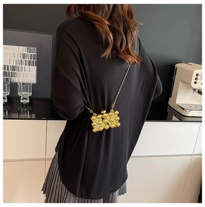 Detail van een gouden mini-acryltas met 3D-bolstructuur en een metalen kettingriem