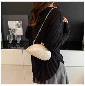Detail view of pearlescent shell-shaped evening bag with gold chain and ball clasp