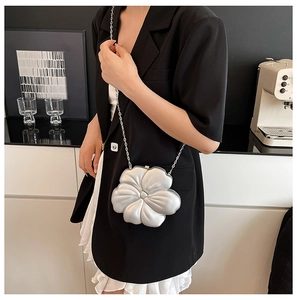 Detail of silver 3D flower evening bag with slim metal chain strap on a model