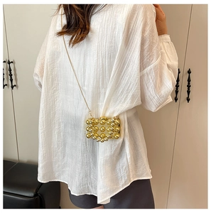 Detail van een elegante mini box tas met witte parels en gouden ketting voor dames