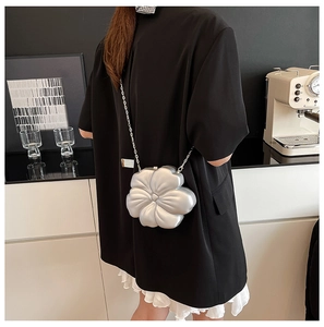 Detail of silver 3D flower crossbody bag with metallic finish and metal chain strap