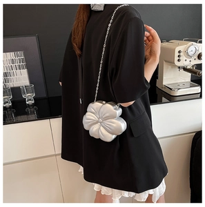 Detail of silver flower clutch bag featuring 3D petal texture and fine metal chain strap