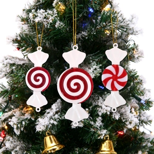 Close-up of red and white peppermint candy ornaments hanging on a snowy Christmas tree