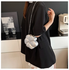 Silver flower-shaped evening clutch bag with chain strap shown in a lifestyle setting