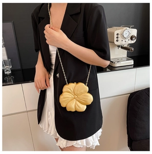 Detail view of a 3D floral evening clutch bag in matte gold finish with chain strap