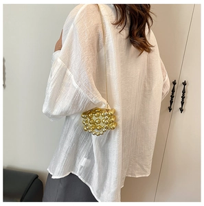 Mini gouden kralen crossbody tas met elegante metalen kettingriem op een model