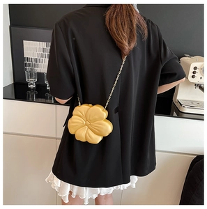 Chic flower-shaped crossbody bag in bright yellow with gold chain on model's back