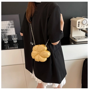 Detail of flower-shaped evening clutch with gold petals and delicate metal chain strap