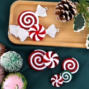 Macro view of festive red, white, and green spiral candy ornaments on green silk fabric