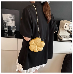 Close-up of yellow flower-shaped evening bag with a gold chain strap on a black blazer