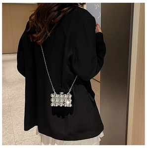 Achteraanzicht van de zilveren mini box bag met metalen parels en ketting op een blazer