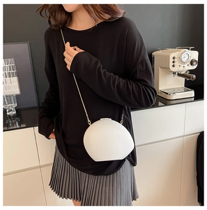 Détail latéral d'un sac en acrylique blanc en forme de coquille avec chaîne dorée
