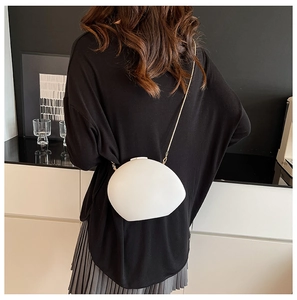 Minimalist white shell-shaped acrylic bag with gold metal chain shown on model