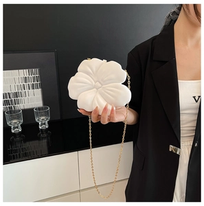 Detailed close-up of a white flower-shaped clutch bag with a detachable gold chain strap