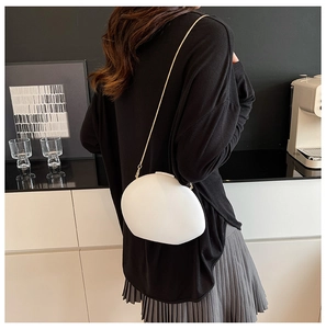 Detailed view of a white pebble-shaped crossbody bag with a slim gold chain strap