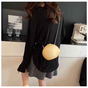 Détail d'un sac bandoulière en acrylique jaune clair en forme de coquillage avec chaîne fine