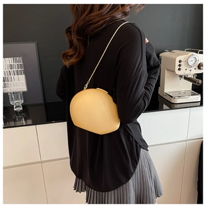 Détail du sac en acrylique beige en forme de galet avec chaîne dorée sur l'épaule
