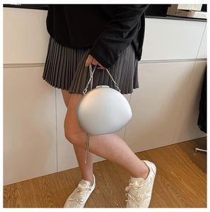 Pochette ovale argentée en acrylique avec fine chaîne en métal portée par un mannequin