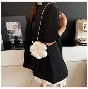 Detail of white 3D flower evening bag with gold chain strap on a black blazer
