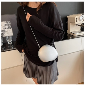 Detail view of a silver irregular shell-shaped crossbody bag with a metal chain