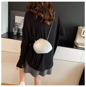 Silver pebble acrylic crossbody bag with metal chain strap worn on back for minimalist look