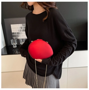 Detail of red acrylic shell bag with gold chain strap against a stylish interior