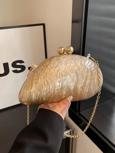 Acrylic evening clutch with gold marble effect and sphere clasp shown in hand