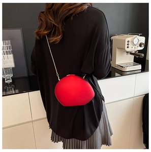 Close-up of red shell-shaped crossbody bag with gold chain strap on model