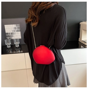 Sac bandoulière en acrylique rouge en forme de galet avec fine chaîne dorée sur mannequin