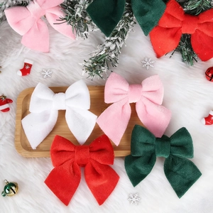 Detail of four velvet Christmas bows in red, green, pink, and white on a festive background