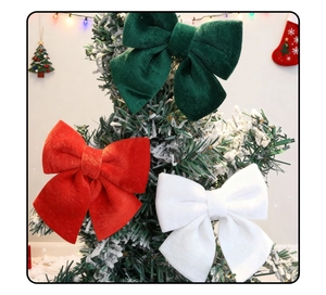 Three premium velvet Christmas bows in red green and white on a snowy festive tree