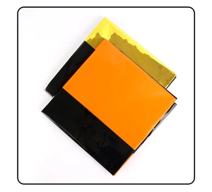 Close-up of stacked disposable tablecloths in black, orange and metallic gold for parties