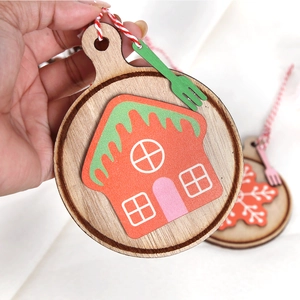 Detail of wooden Christmas ornament featuring a gingerbread house and red cotton string